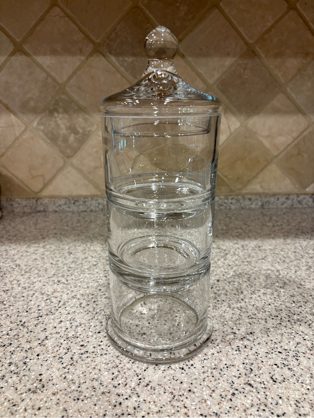 Clear glass stackable storage jar features three tiers with a matching lid